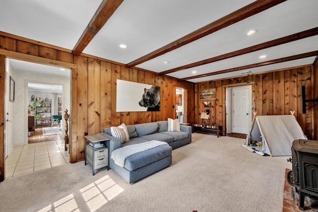 living area featuring beam ceiling, recessed lighting, light colored carpet, wood walls, and a wood stove