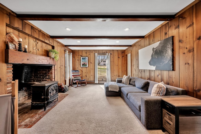 living area featuring light colored carpet, wood walls, a wood stove, and beam ceiling