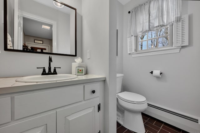 half bathroom featuring a baseboard heating unit, vanity, and toilet