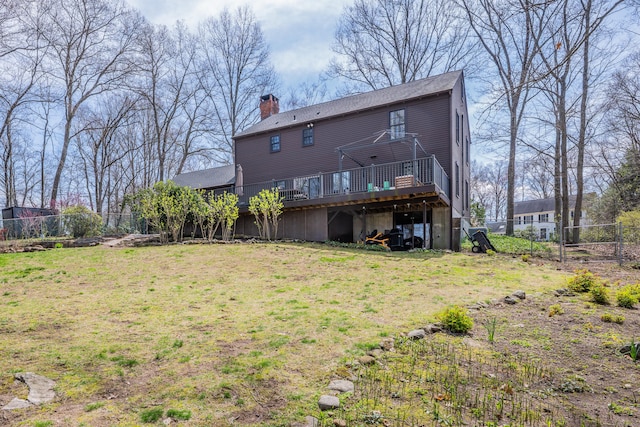 back of house featuring fence, a wooden deck, a lawn, and a chimney