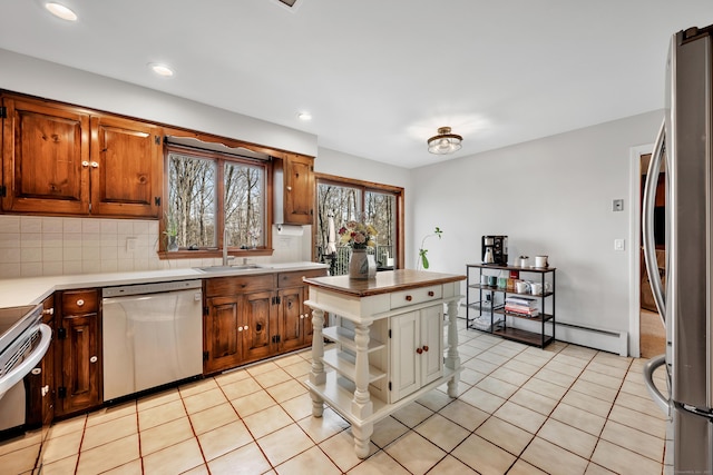 kitchen featuring stainless steel appliances, a sink, backsplash, and light tile patterned flooring