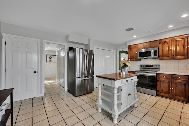 kitchen featuring stainless steel appliances, open shelves, light tile patterned flooring, decorative backsplash, and wood counters