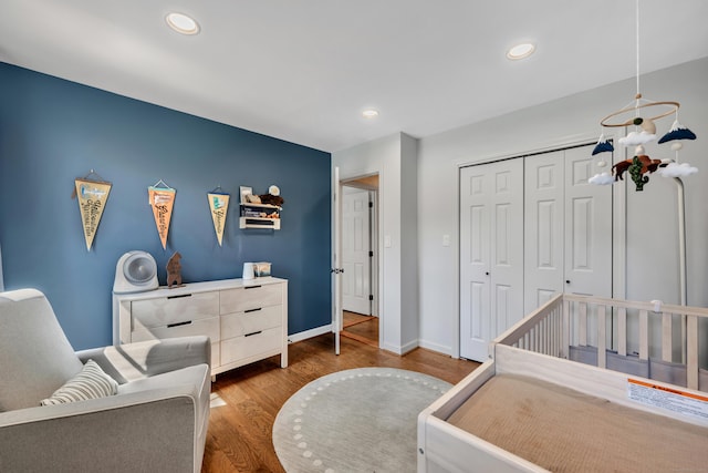 bedroom featuring baseboards, wood finished floors, recessed lighting, and a closet