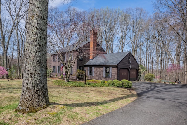 view of property exterior with a chimney, aphalt driveway, and a yard