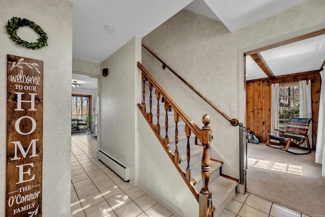 stairway with baseboard heating, wooden walls, and tile patterned flooring