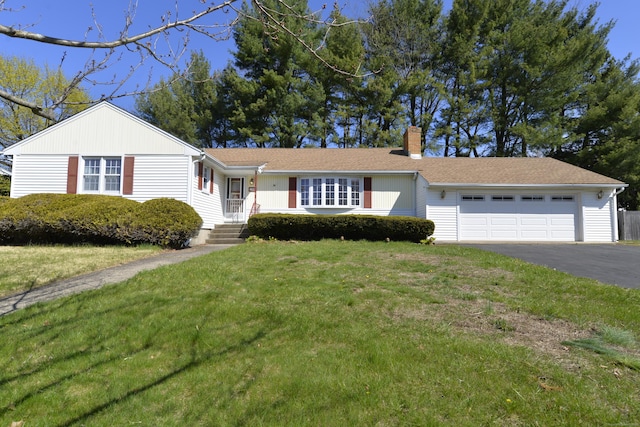 ranch-style home featuring a chimney, a garage, aphalt driveway, and a front lawn