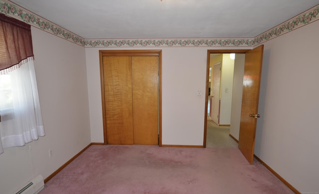 unfurnished bedroom featuring a closet, baseboards, baseboard heating, and light carpet