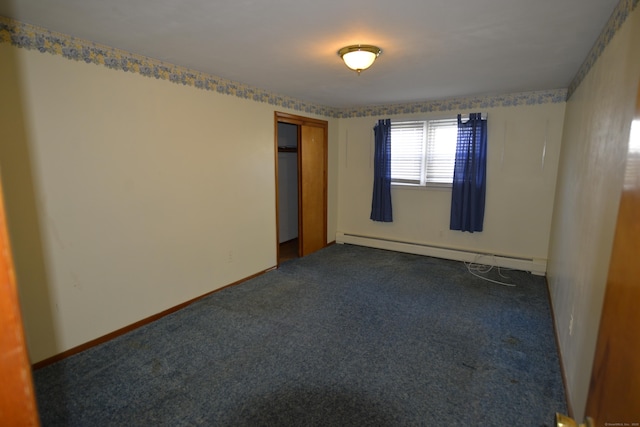 empty room featuring baseboard heating and dark colored carpet