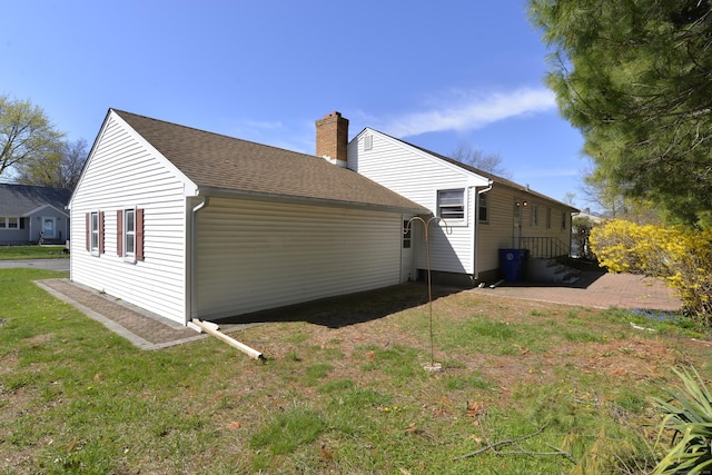 view of home's exterior with a chimney, a shingled roof, and a yard