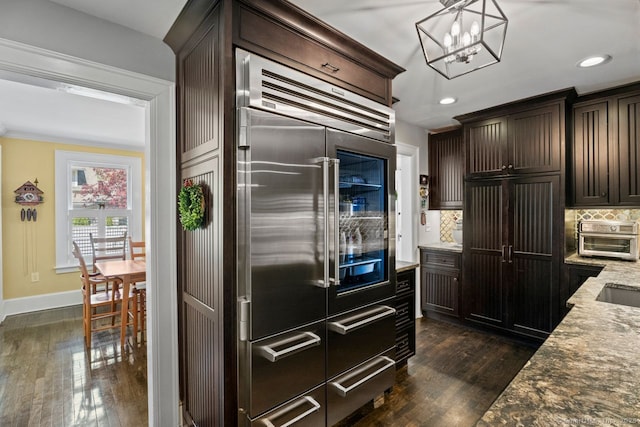 101 N Main St, Essex, CT 06426 - kitchen with built in refrigerator, decorative backsplash, dark wood-style floors, dark brown cabinetry, and light stone countertops