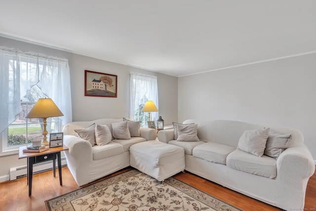 living area with ornamental molding, light wood-style flooring, and a baseboard heating unit