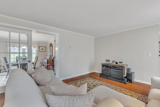 living area featuring crown molding, baseboards, and wood finished floors
