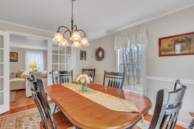 dining area with ornamental molding, wood finished floors, and a chandelier