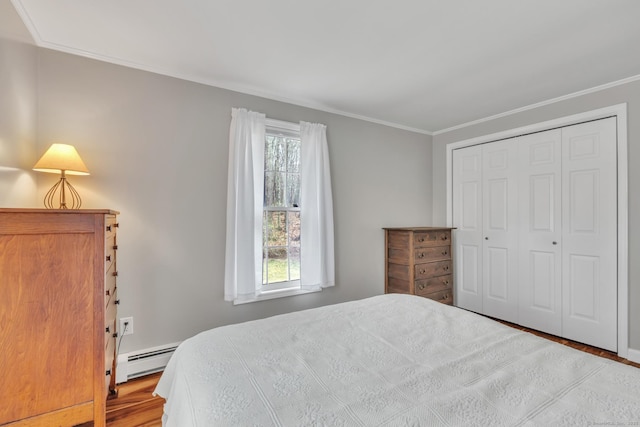 bedroom with crown molding, a closet, a baseboard heating unit, and wood finished floors
