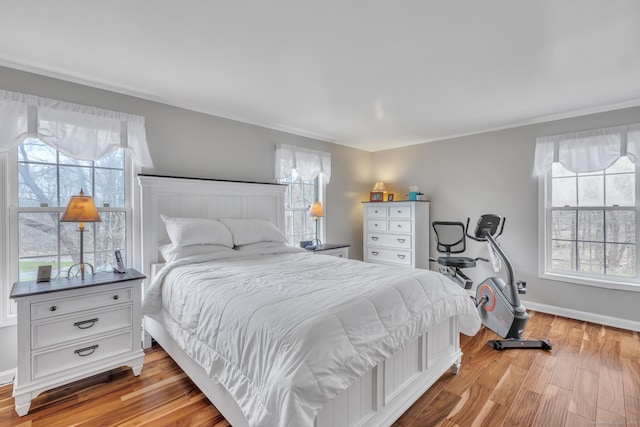 bedroom with baseboards, light wood finished floors, and multiple windows