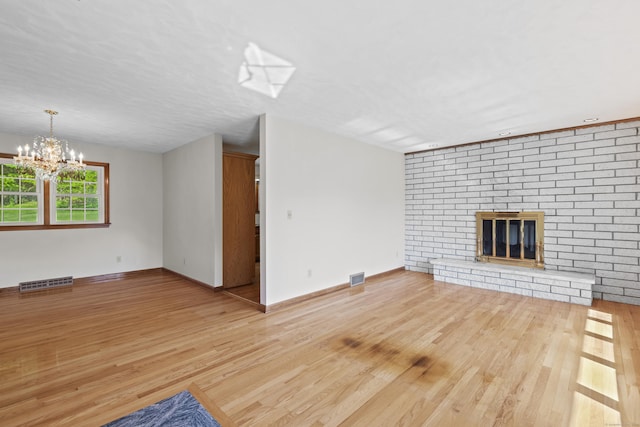 246 Sea Hill Rd, North Branford, CT 06471 - unfurnished living room with wood finished floors, a chandelier, a brick fireplace, and baseboards