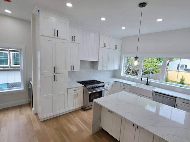 kitchen featuring stainless steel appliances, a sink, light wood finished floors, backsplash, and recessed lighting