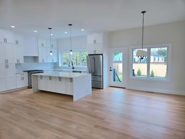 kitchen with high quality appliances, a center island, white cabinetry, light countertops, and decorative backsplash