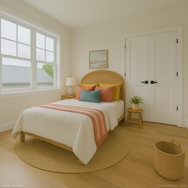 bedroom featuring light wood-type flooring, baseboards, and a closet