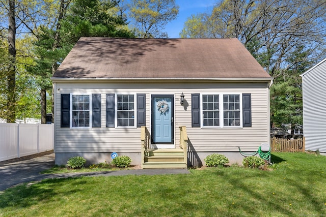 cape cod house featuring fence and a front lawn