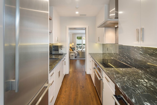 2 Mead St Unit 20, New Canaan, CT 06840 - kitchen with stainless steel appliances, wall chimney exhaust hood, dark wood-style flooring, dark stone countertops, and white cabinets