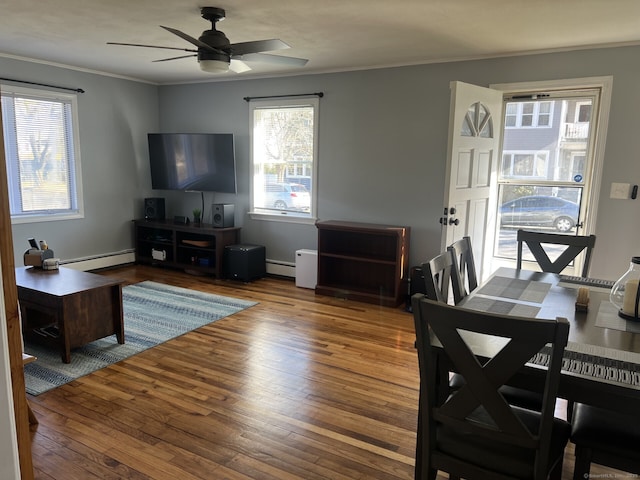 living room with ceiling fan, crown molding, wood-type flooring, and a baseboard heating unit
