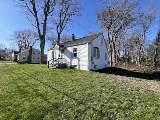 view of side of property featuring a chimney and a lawn
