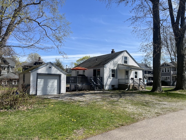 view of front facade with a chimney, driveway, an outbuilding, and a garage