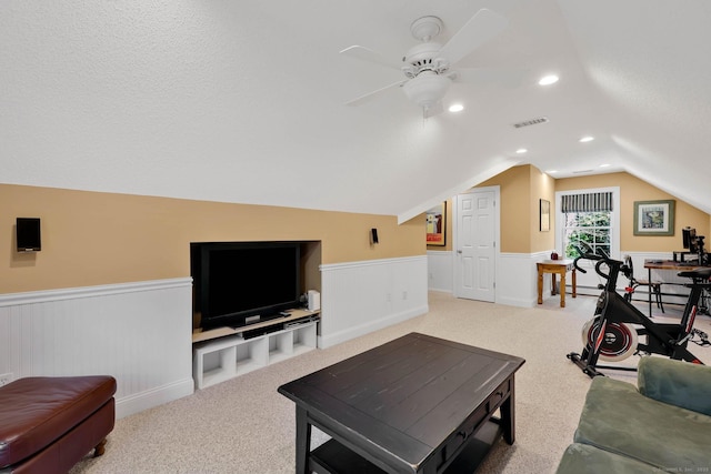 living area featuring ceiling fan, visible vents, vaulted ceiling, a wainscoted wall, and carpet