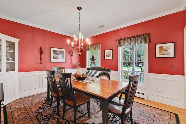 dining room with an inviting chandelier, wainscoting, light wood-type flooring, visible vents, and ornamental molding