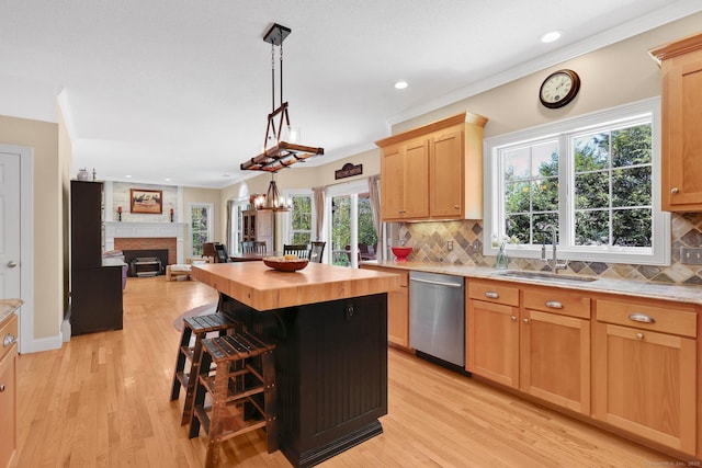 kitchen with a sink, a fireplace, wooden counters, open floor plan, and stainless steel dishwasher