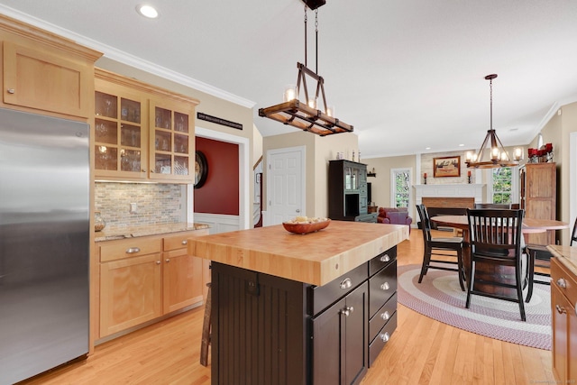 kitchen with crown molding, wooden counters, light wood finished floors, and stainless steel refrigerator
