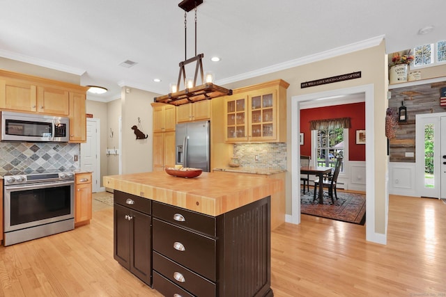 kitchen featuring crown molding, stainless steel appliances, wood counters, and a wealth of natural light