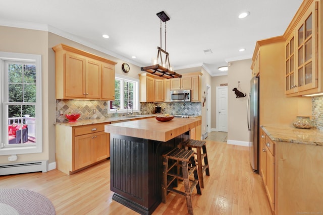 kitchen with light brown cabinetry, appliances with stainless steel finishes, a sink, butcher block counters, and light wood-style floors