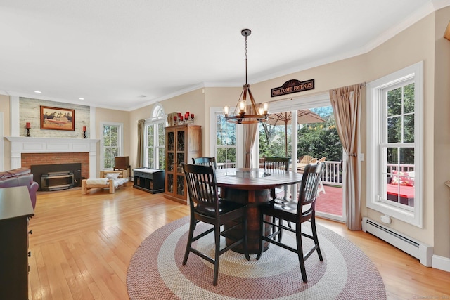 dining space with light wood-type flooring, a baseboard radiator, a notable chandelier, and ornamental molding