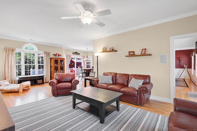 living room with light wood-style floors, crown molding, and ceiling fan with notable chandelier