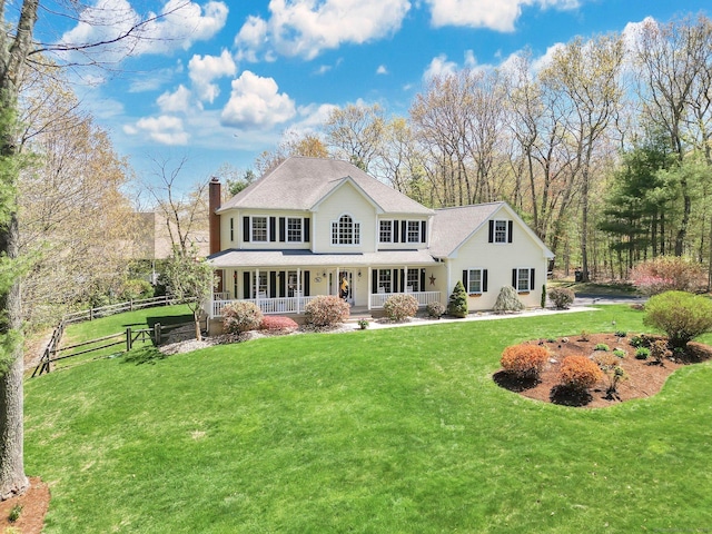 rear view of property featuring a porch, a chimney, roof with shingles, a lawn, and fence