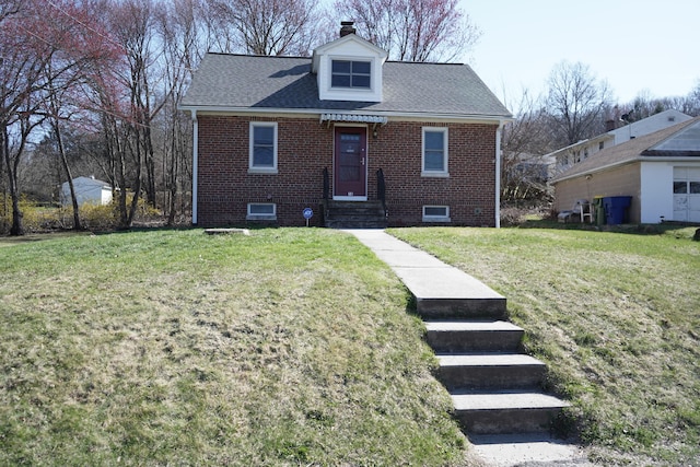 view of front of property with brick siding, a chimney, a front lawn, and a shingled roof