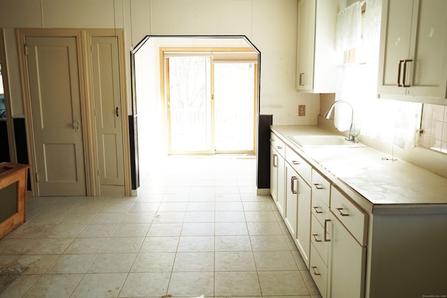 kitchen with light countertops, a healthy amount of sunlight, light tile patterned floors, and a sink