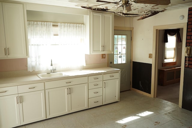 kitchen with a ceiling fan, light countertops, a sink, and tasteful backsplash