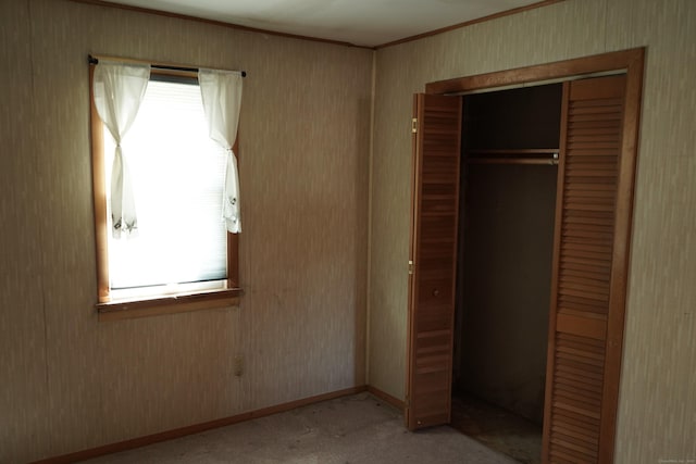 unfurnished bedroom with baseboards, light colored carpet, a closet, and ornamental molding