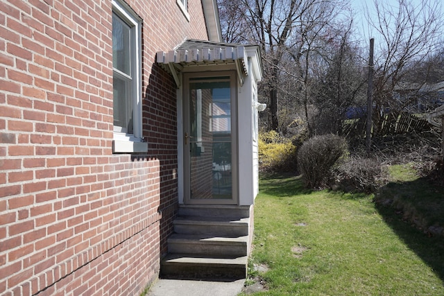 property entrance with a lawn and brick siding