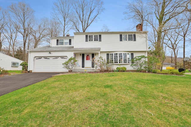 traditional-style house with an attached garage, a chimney, a front lawn, and aphalt driveway