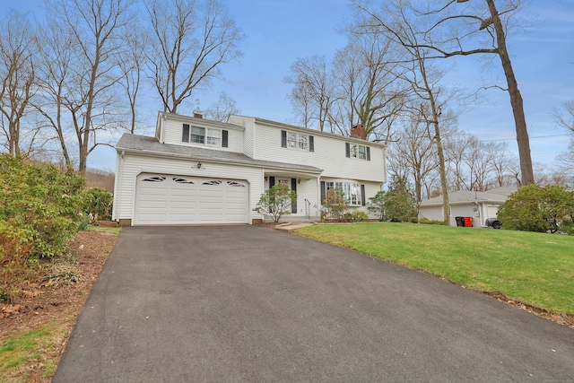 view of front facade with a front lawn, driveway, and a chimney