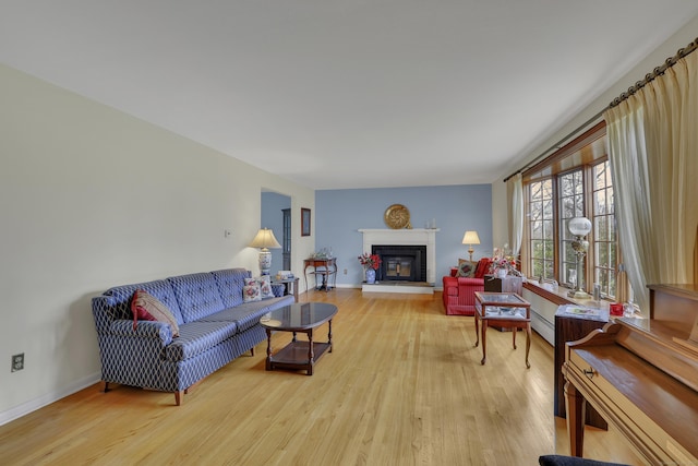 living room with baseboards, a glass covered fireplace, and wood finished floors