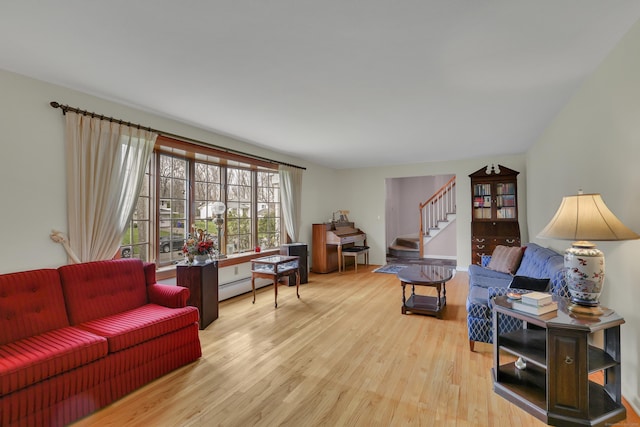living room featuring a baseboard heating unit, stairs, and wood finished floors