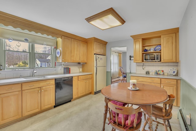 kitchen with a sink, stainless steel microwave, freestanding refrigerator, a baseboard heating unit, and black dishwasher