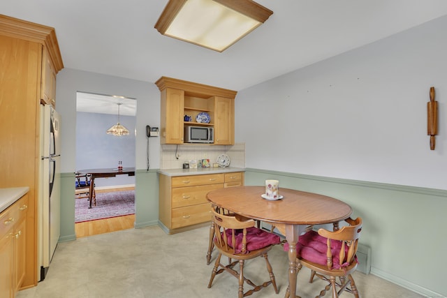 dining area with baseboards and light colored carpet
