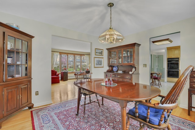 dining room with light wood-style flooring and a notable chandelier