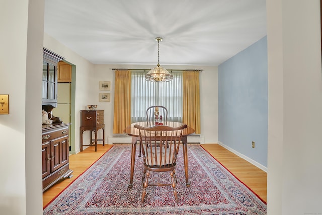 dining space featuring baseboard heating, baseboards, an inviting chandelier, and light wood-style flooring